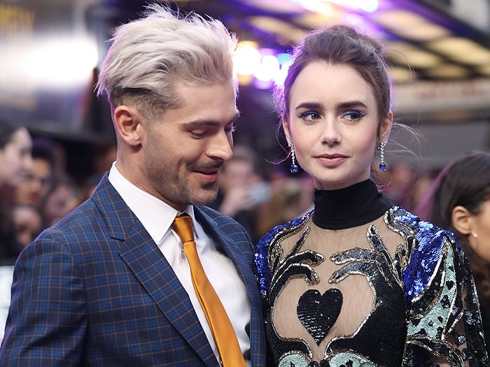 Zac Efron sports a bold platinum blonde hairstyle, while Lily Collins complements her look with an elegant, textured updo