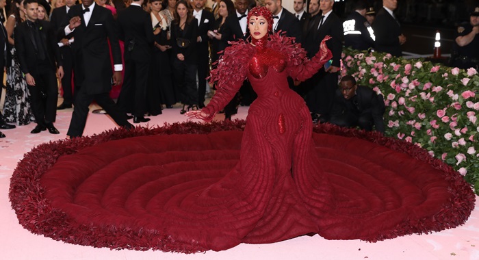 Cardi B commands the 2019 Met Gala in a custom oxblood Thom Browne gown, its enormous feather-trimmed train creating a dramatic circular silhouette around her