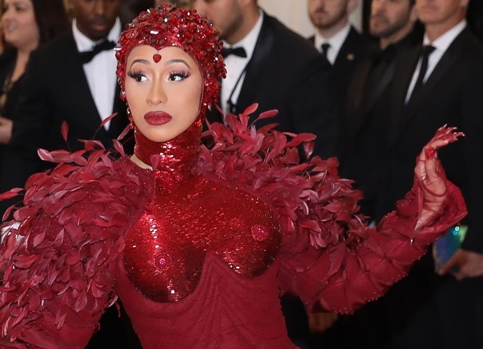 Cardi B’s custom Met Gala look pairs Thom Browne’s feathered oxblood design with a beaded headpiece and 44-carat ruby nipple jewelry by Stefere