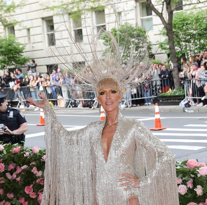 Céline Dion arrives at the 2019 Met Gala in a custom Oscar de la Renta couture look inspired by the Ziegfeld Follies, featuring a hand-embroidered metallic fringe gown that required more than 3,000 hours of work by 52 master embroiderers and a dramatic Noel Stewart feathered headpiece