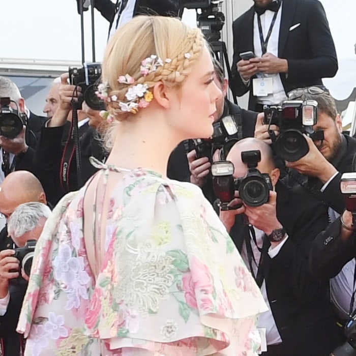 A side profile highlights Elle Fanning’s braided crown adorned with tiny flowers, a pastoral beauty detail that echoed the botanical motifs of her Valentino couture ensemble at Cannes 2019
