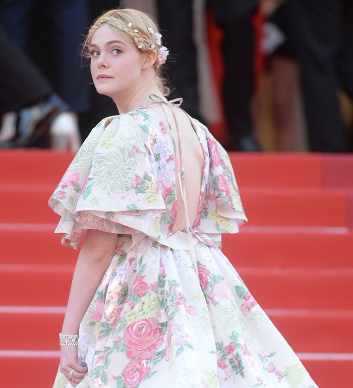 Turning to reveal the gown’s open back and layered cape sleeves, Elle Fanning showcases the couture craftsmanship and delicate structure that defined her fairy-tale Cannes moment