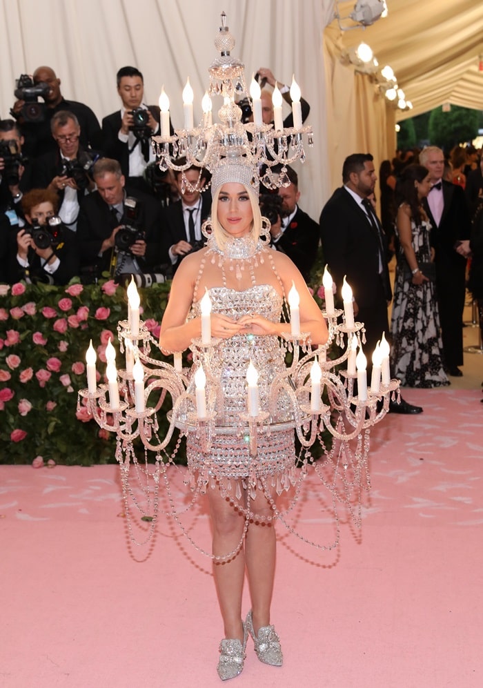 Katy Perry lit up the 2019 Met Gala in a crystal-embellished Moschino chandelier dress paired with equally dazzling, jewel-encrusted mules that perfectly captured the camp theme’s extravagant spirit