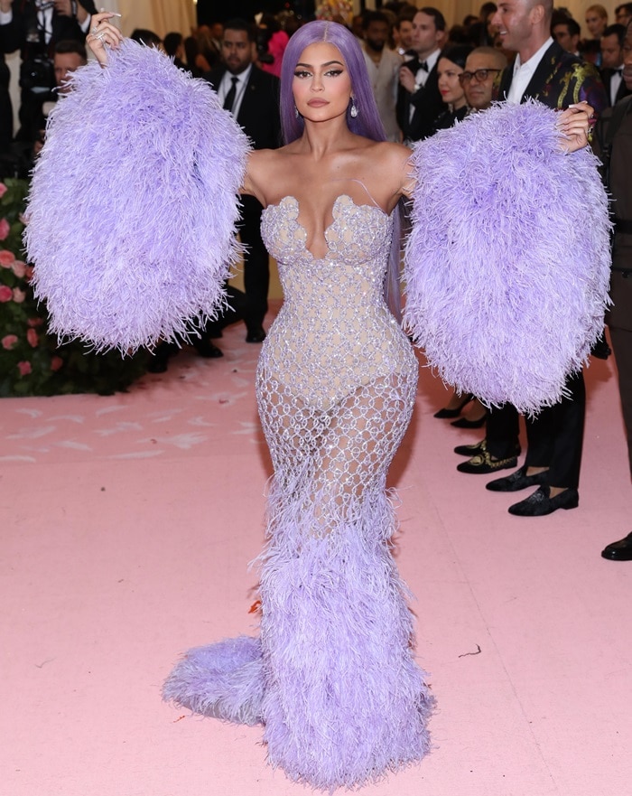 Kylie Jenner dazzled in a custom lavender Versace gown adorned with crystal netting and feathered accents, accessorized with $4.9 million worth of Lorraine Schwartz jewelry and hidden beige heels