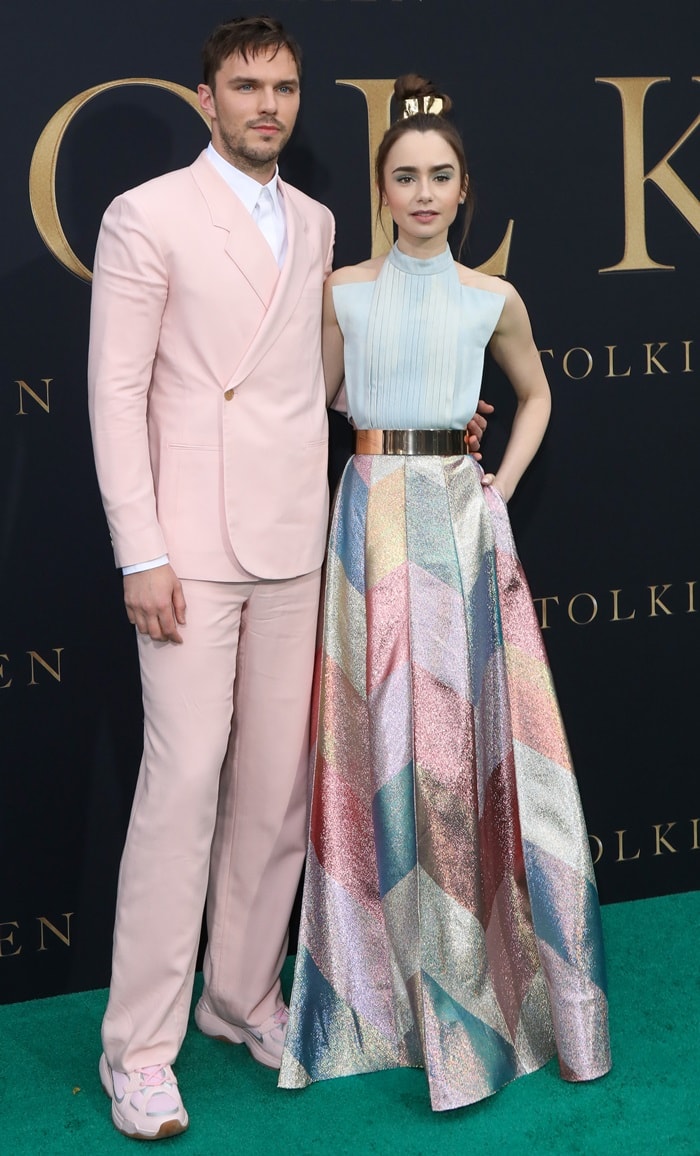 Lily Collins arrived at the Tolkien premiere in Westwood on May 8, 2019, wearing a pastel Ronald van der Kemp haute couture gown with a shimmering geometric skirt and metallic waist belt, while Nicholas Hoult complemented the playful color palette in a blush pink Dior Men suit styled with matching Dior B24 sneakers