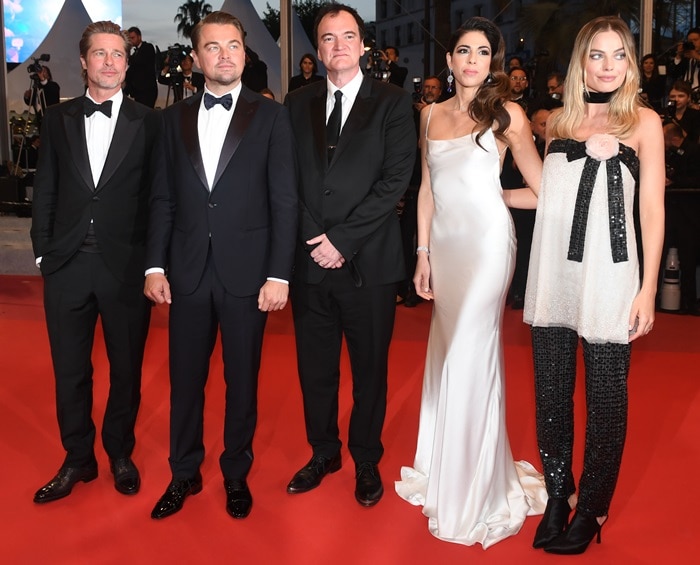Margot Robbie anchors her Chanel Haute Couture tunic-and-trouser look with sleek black satin mules, adding minimalist polish alongside co-stars Leonardo DiCaprio and Brad Pitt at the Cannes premiere of Once Upon a Time in Hollywood