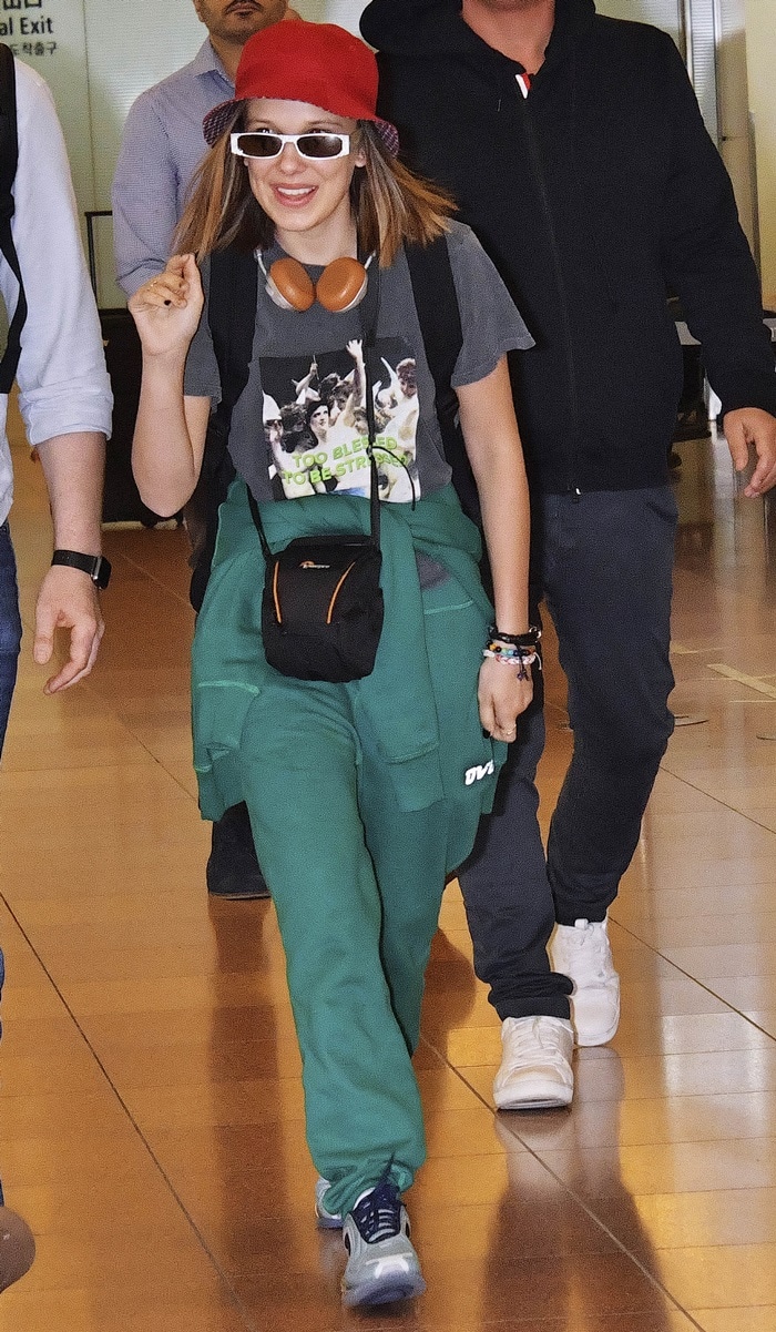 Millie Bobby Brown touches down in Tokyo wearing forest-green OVO sweats and a pair of easy, travel-ready silver-and-blue sneakers