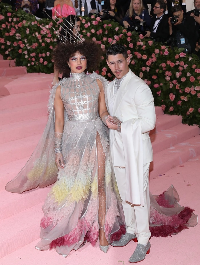 Priyanka Chopra and Nick Jonas make a striking pair at the 2019 Met Gala, embracing the 'Camp: Notes on Fashion' theme with Priyanka's avant-garde Dior Haute Couture gown and Nick's dapper all-white Dior suit with glittering silver shoes