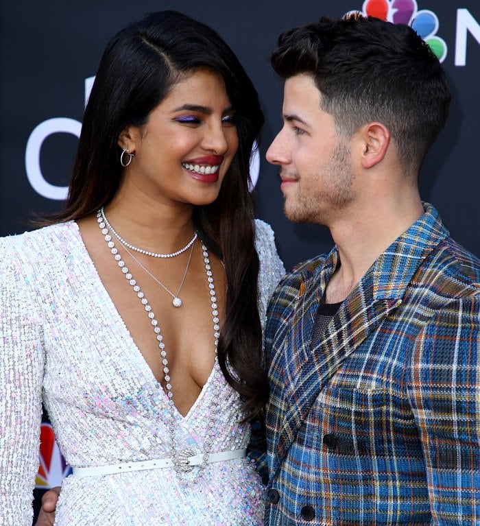 Priyanka Chopra wears layered diamond necklaces that frame the deep V neckline of her sequined Zuhair Murad gown, adding vertical sparkle that elongates her silhouette alongside her transparent heels