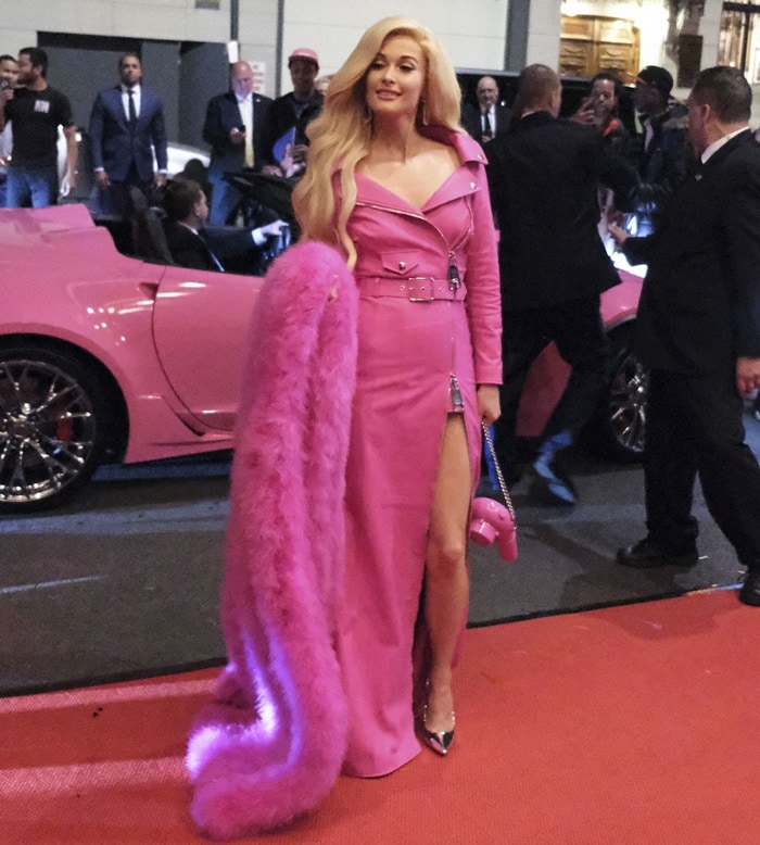 Kacey Musgraves arrives at her hotel in a Barbie-inspired Moschino look, carrying a whimsical hot pink hairdryer bag and wearing silver Aldo pointed-toe pumps