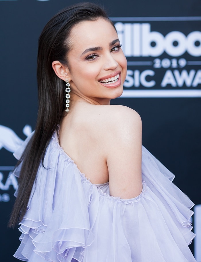 Sofia Carson glowed on the red carpet, pairing her one-shouldered lavender ruffled gown with sparkling Moonlight earrings