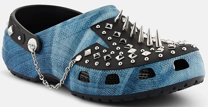 Crocs' denim-print clog goes full punk with a black leather overlay studded in mixed-metal spikes and finished with a silver chain strap