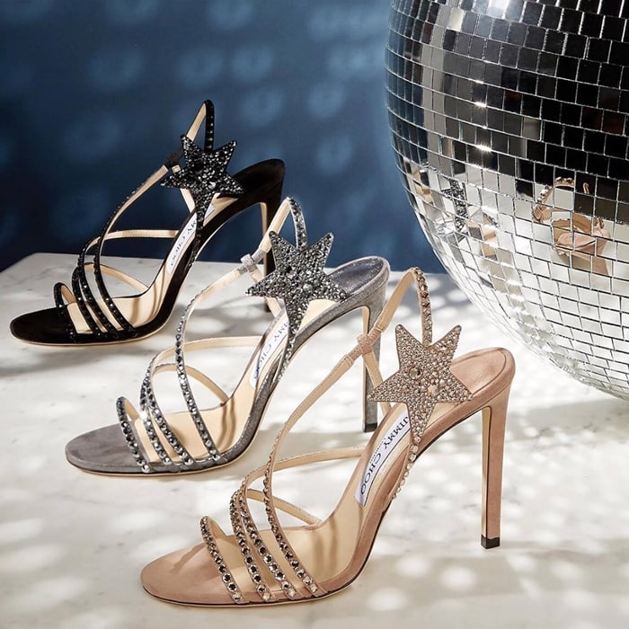 Jimmy Choo's Lynn sandals paired delicate crystal-encrusted straps with a signature star-shaped ankle embellishment, transforming the minimalist stiletto silhouette into a playful celestial-inspired statement piece available in black suede, silver glitter, and blush satin finishes.