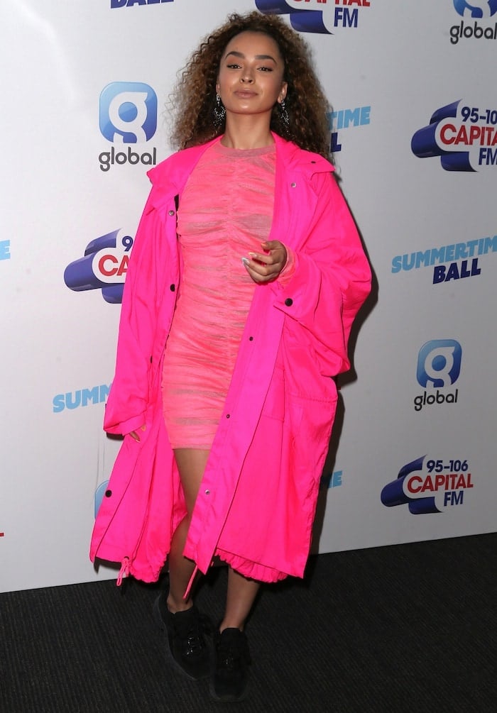 Ella Eyre makes a bold statement at the Summertime Ball, pairing a hot pink House of Holland bodycon dress and oversized raincoat with chunky black Acne Studios Manhattan platform sneakers for a street-chic finish