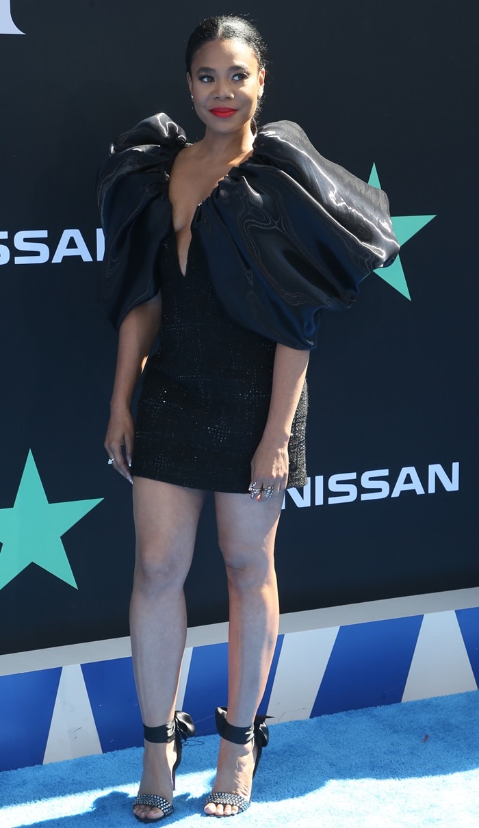 Facing forward on the blue carpet, Regina Hall balances exaggerated volume with precise ankle-tie sandals, the delicate bows softening the sharp, architectural silhouette of her dress