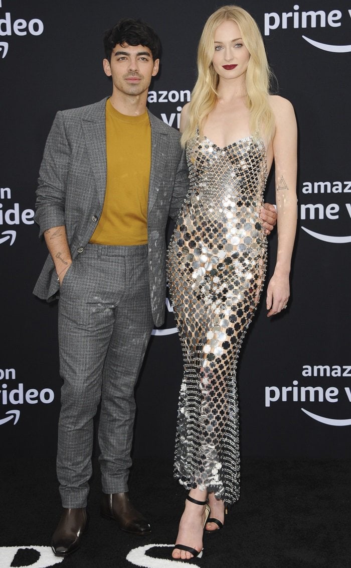 Sophie Turner towered over Joe Jonas in her sky-high black ankle-strap heels and shimmering Paco Rabanne gown, while he complemented her glam in a tailored gray check suit from the Ermenegildo Zegna XXX collection, styled with a mustard knit and polished brown leather Chelsea boots