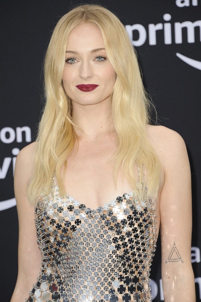 Sophie Turner subtly showcased the minimalist infinite triangle tattoo on her upper left arm, a geometric design she debuted in July 2018 that adds a personal edge to her polished red-carpet style