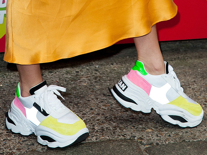 A close-up highlights the layered white, pink, neon yellow, and green panels, thick laces, and sculpted lug soles of Lottie Moss’s DSquared2 Giant Hike sneakers