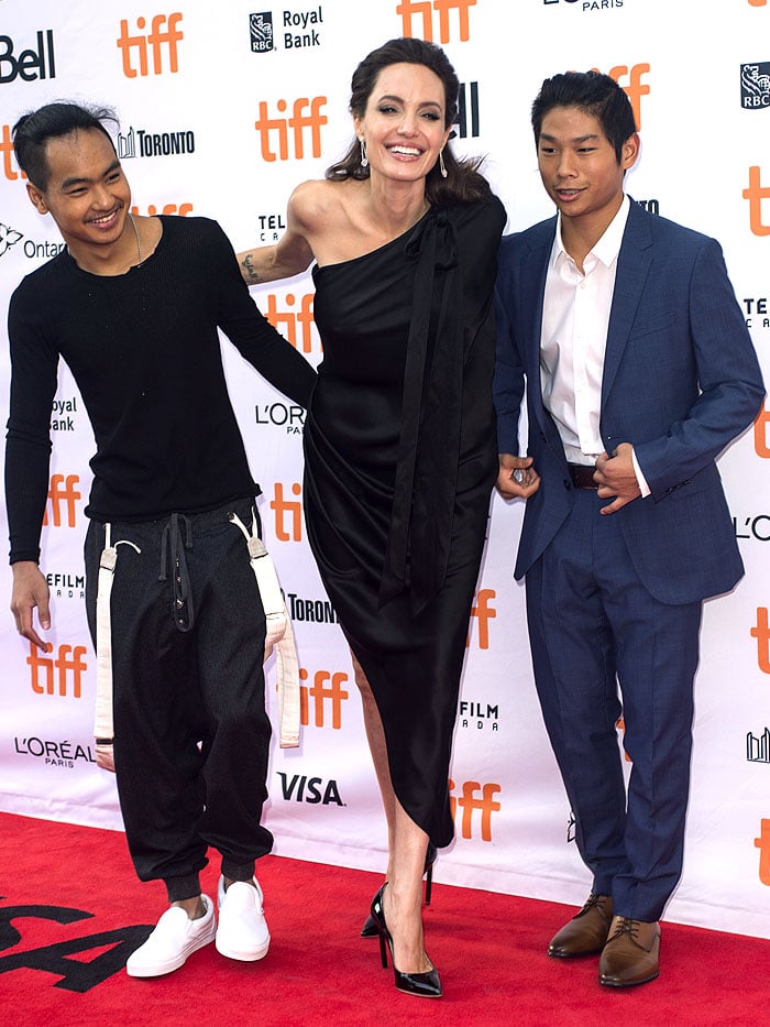 Angelina Jolie radiates elegance in a one-shoulder Ralph Russo bow dress and Saint Laurent ‘Paris’ pumps, joined by sons Maddox and Pax—each showing off their unique style—at the First They Killed My Father premiere during TIFF on September 11, 2017