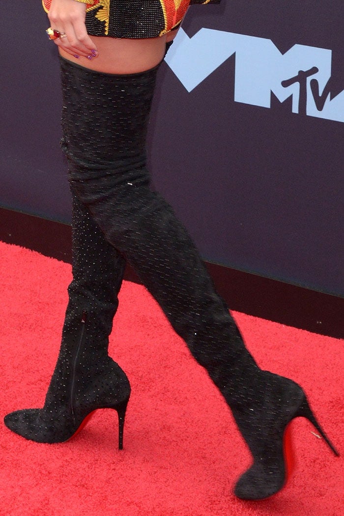 Christian Louboutin Elouix boots bring black crystals, pointed toes, towering stiletto heels, and flashes of the designer’s signature red soles to Swift’s VMAs look