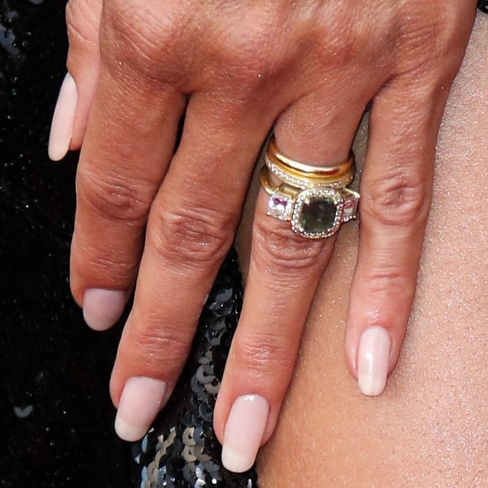 A close-up of Heidi Klum’s stacked rings reveals a striking green center stone surrounded by pavé accents, paired with a soft nude manicure for contrast