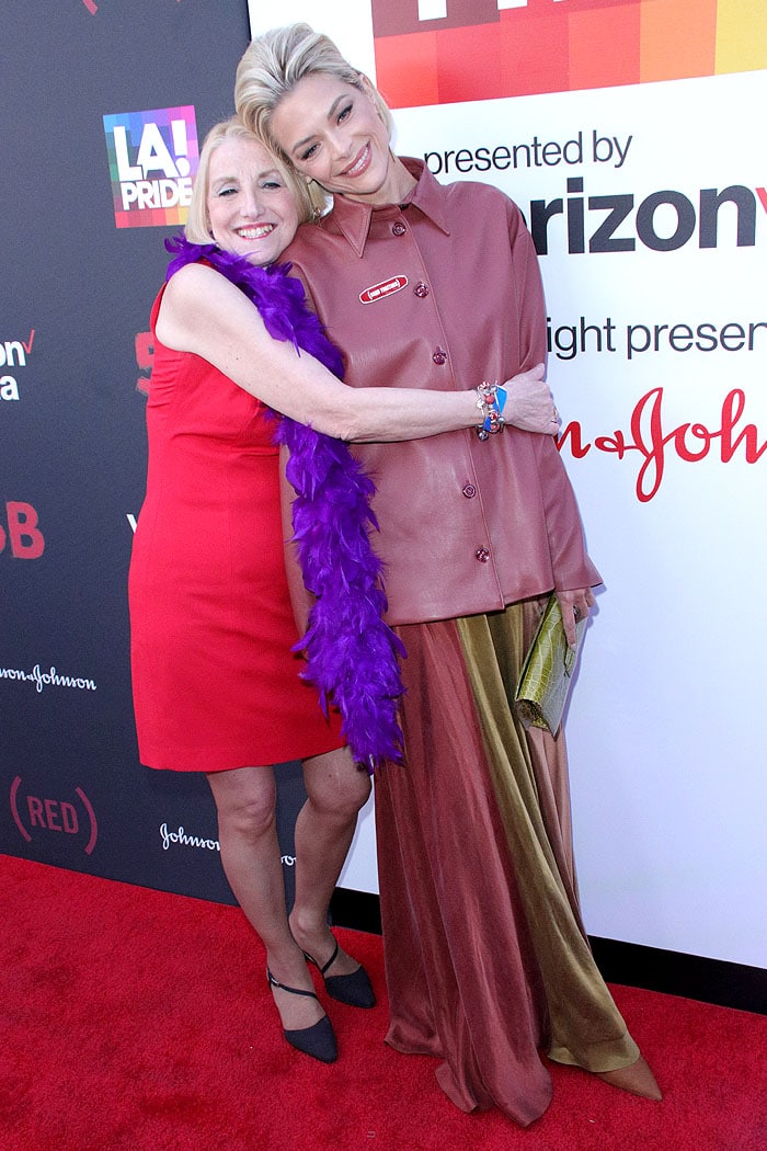 Jaime King embraces AIDS activist Rita Rockett in a bold, color-blocked look, pairing a maroon leather shirt with a fluid two-tone skirt for the 5B premiere at LA Pride 2019