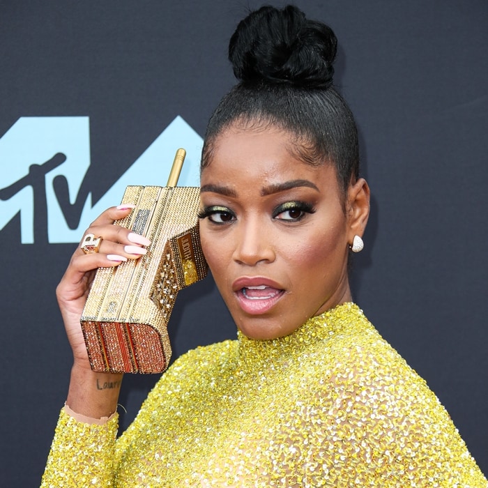 Keke playfully poses with her Judith Leiber brick-phone clutch, fully beaded in Austrian crystals