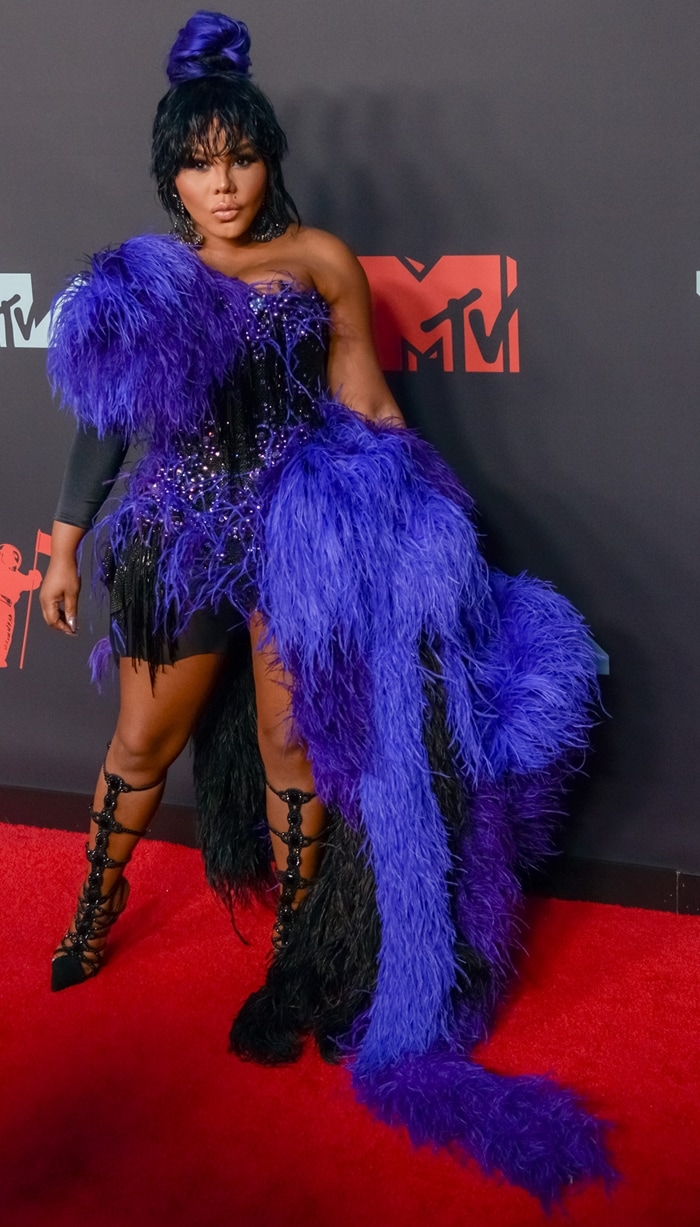Lil’ Kim makes a dramatic entrance at the 2019 MTV Video Music Awards in Newark, pairing a purple-and-black feathered mini dress by The Blonds with strappy black lace-up stiletto heels that highlight her legs