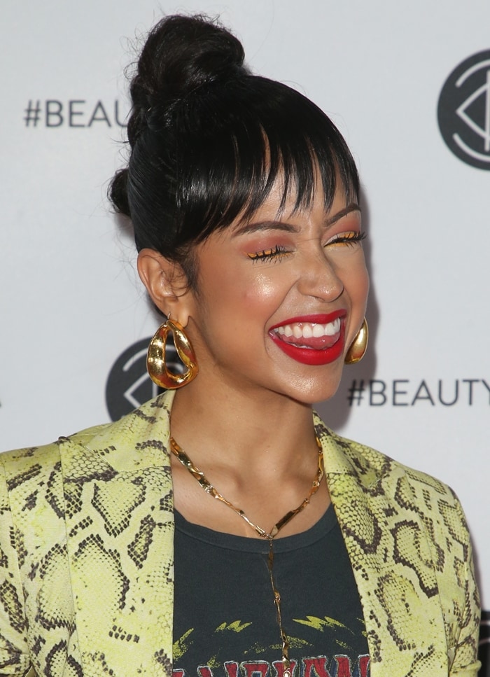 Liza Koshy complements her neon tailoring with sculptural gold hoops and warm-toned glam