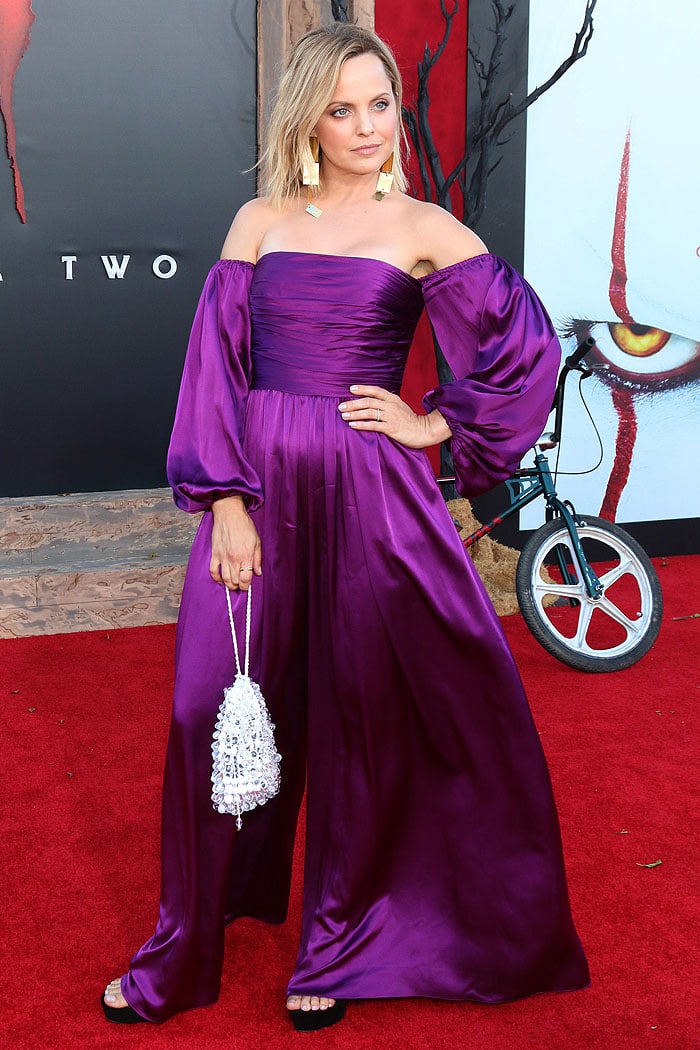 Mena Suvari's off-shoulder purple AMUR jumpsuit at the It: Chapter Two premiere on August 26, 2019, overwhelmed her petite 5'3" frame with its voluminous sleeves and wide-leg pants