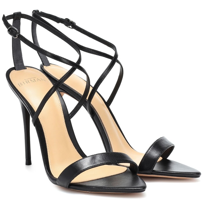 The Alexandre Birman “Smart Cocktail” sandals feature a minimalist black leather design with slim straps and a sharply tapered toe