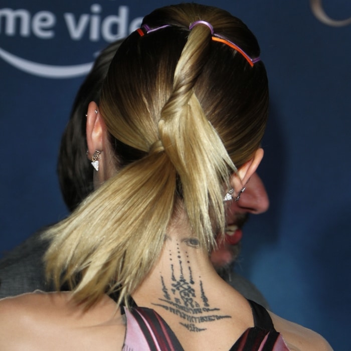 Cara Delevingne’s pulled-back blonde hair reveals her Sak Yant-inspired upper-back tattoo