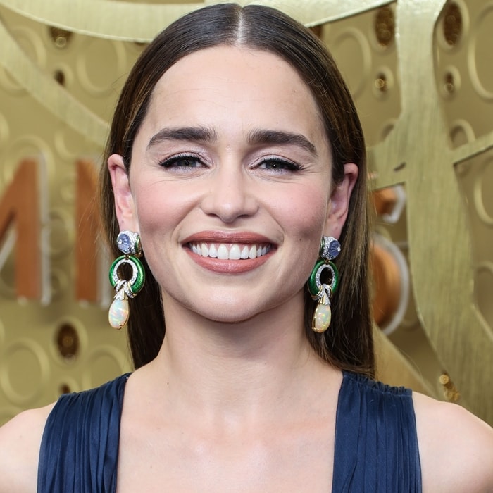 Her David Webb drop earrings—opal, sapphire, and diamond set in yellow gold—add color and texture that lift the minimalist neckline without competing with it