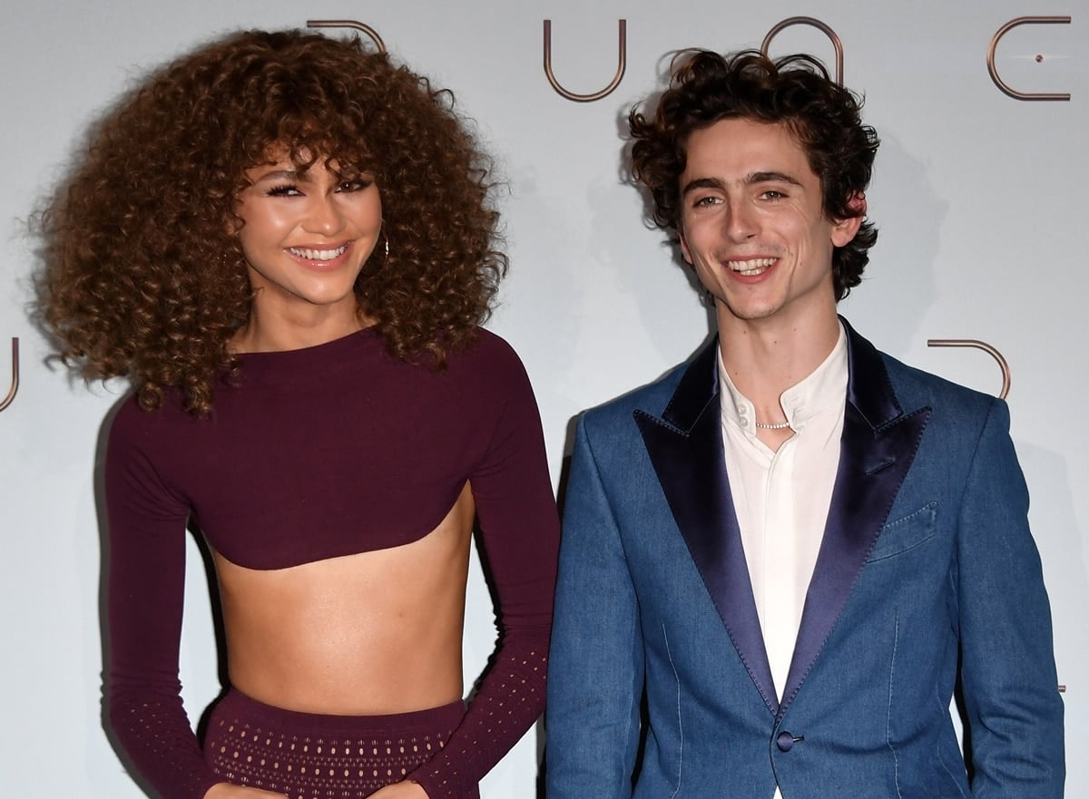 Zendaya radiates in a bold cutout crop top and matching skirt, while Timothée Chalamet opts for a stylish blue suit at a Dune press event, showcasing their playful chemistry