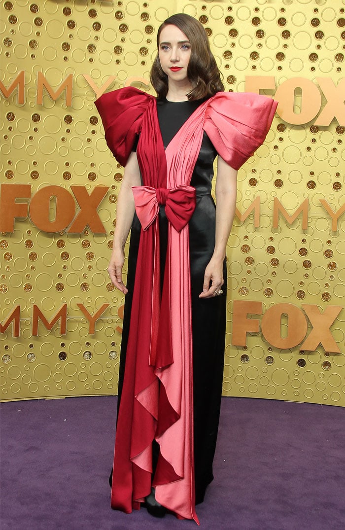 Zoe Kazan brings sculptural drama to the 2019 Emmy Awards in a Gucci gown, where bold pink-and-red ribboned panels and exaggerated bow detailing frame a sleek black silhouette with striking, architectural contrast