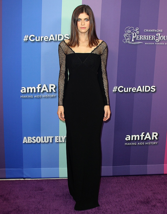 Alexandra Daddario exudes gothic elegance in a black Escada gown with intricate lace sleeves, perfectly balancing simplicity and drama at the 10th Annual amfAR Gala in Los Angeles