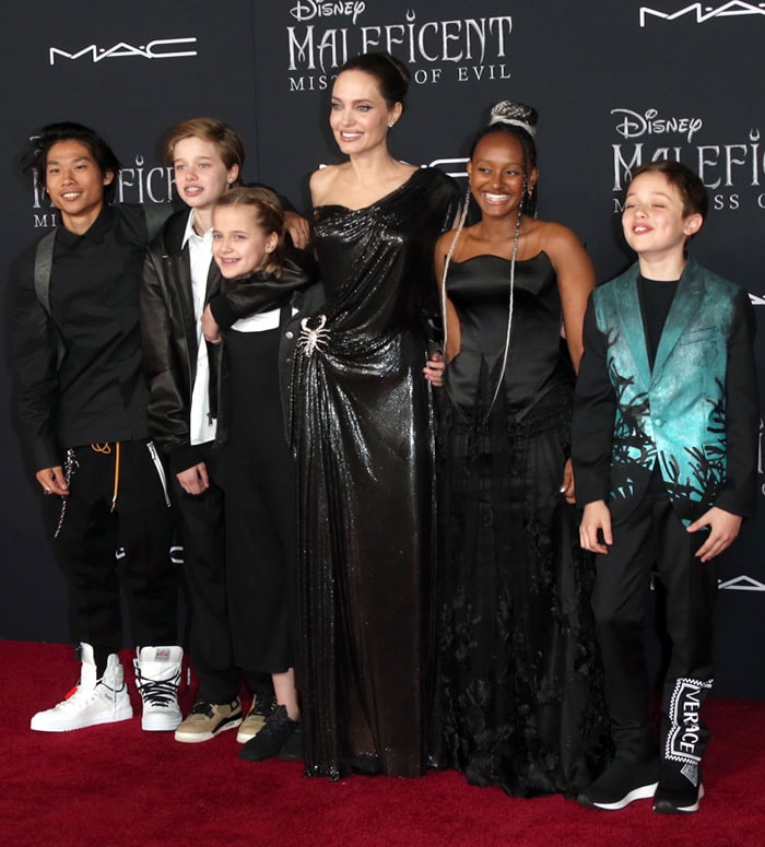 Framed by her children, Angelina Jolie’s monochrome red-carpet styling feels both intimate and theatrical, echoing the film’s dark fantasy aesthetic