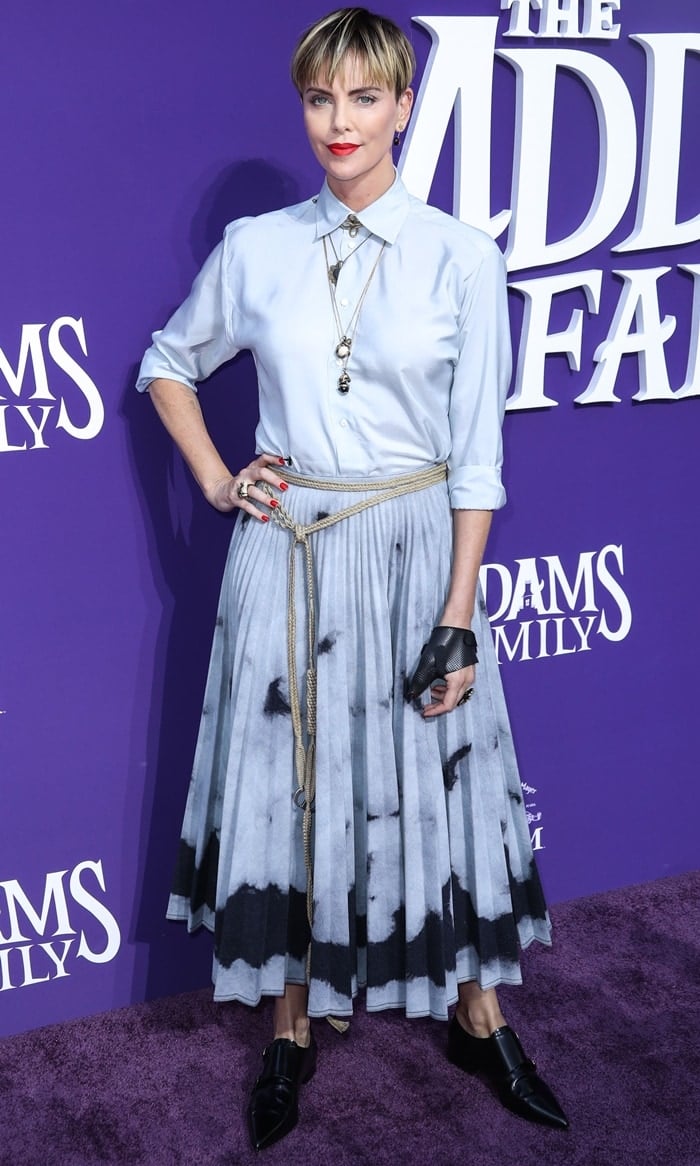 Charlize Theron paired a pleated tie-dye Dior skirt with sleek black pointy-toe shoes, adding edge to her look with a leather mesh glove and bold red lip