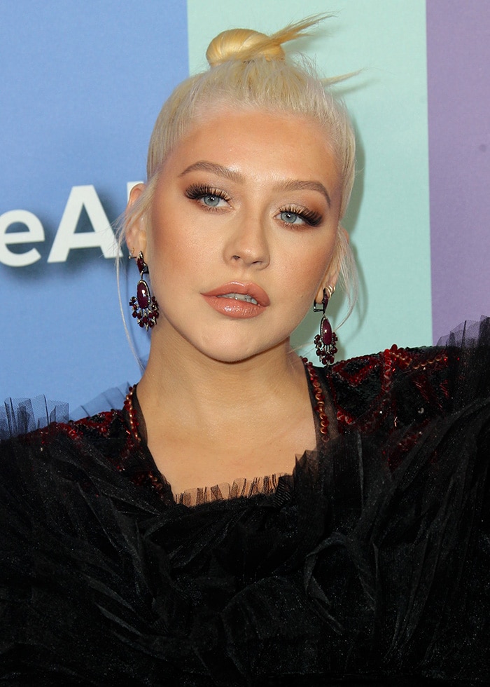 Christina Aguilera stuns with bold eye makeup featuring dramatic lashes and perfectly blended smokey eyeshadow, complemented by glossy nude lips