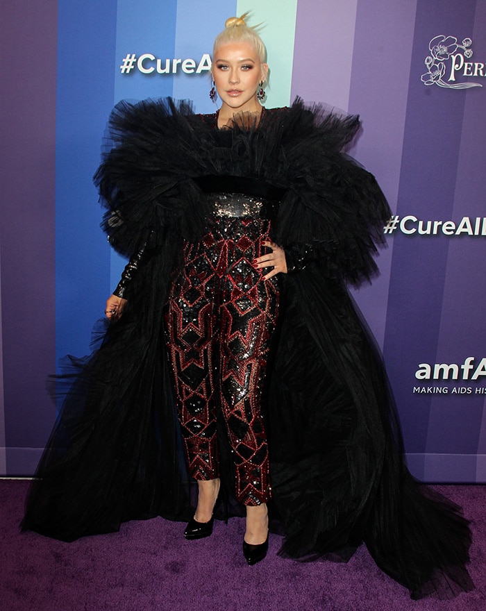 Christina Aguilera turns heads in a dramatic sequined jumpsuit with a voluminous tulle cape by Nicolas Jebran, paired with classic black Saint Laurent pumps at the 10th Annual amfAR Gala in Los Angeles