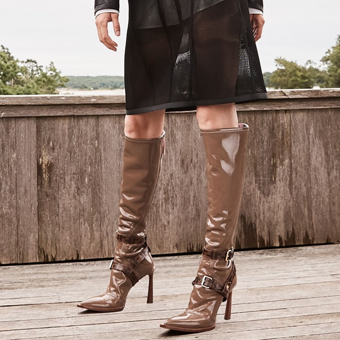 Fendi's brown glossed-neoprene knee boots feature pointed toes, high stiletto heels, and harness-style buckle straps for a bold, rain-ready runway look