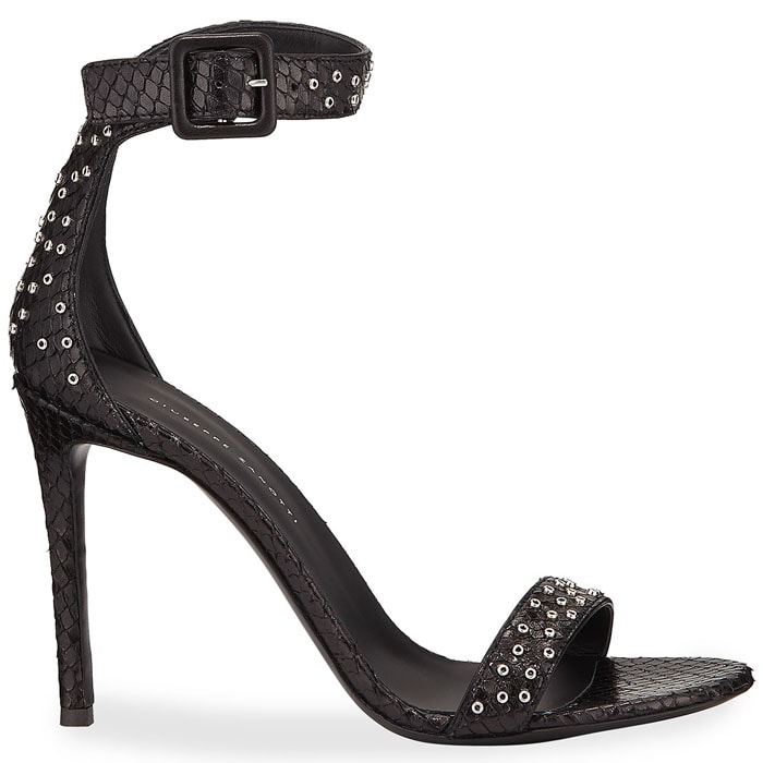 In black, the same Giuseppe Zanotti silhouette takes on a sharper, more understated edge, with tonal snake texture and scattered metal studs emphasizing the minimalist, high-impact design