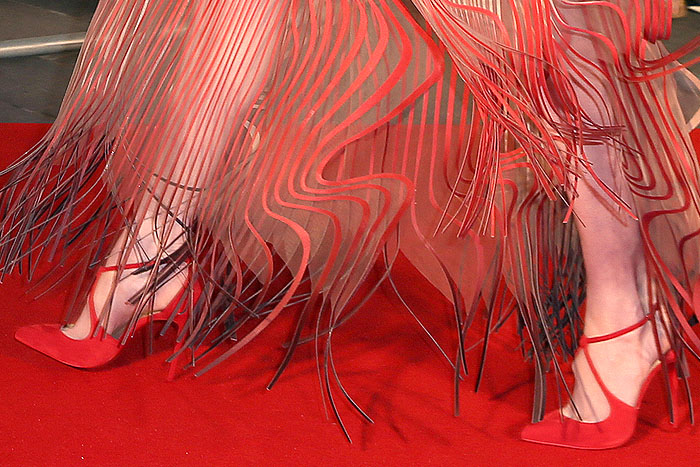The pointed-toe Christian Louboutin 'Alminetta' pumps feature elegant knotted ankle straps and rich red suede, chosen to complement the gown's crimson hem without distracting from its fluid design