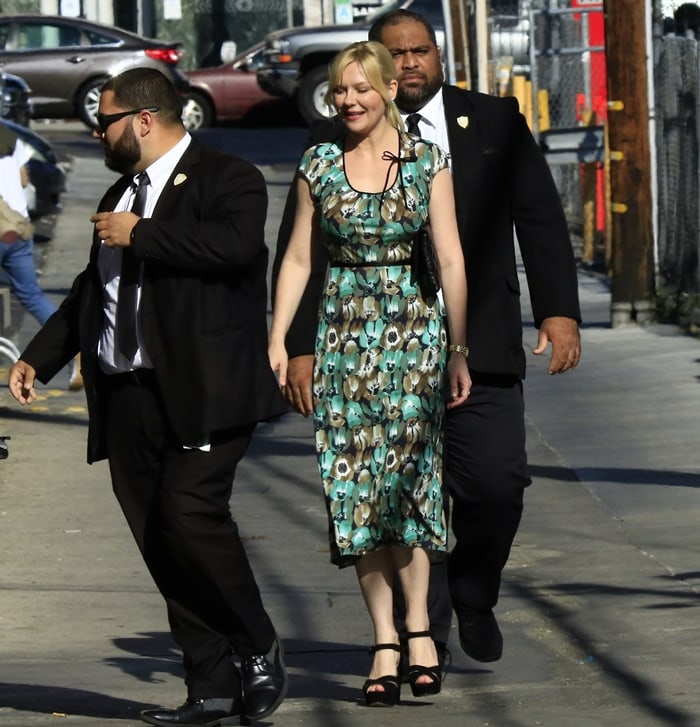 Kirsten Dunst steps into the Jimmy Kimmel Live! studio in a floral Prada dress, grounded by black ankle-strap platform heels that add structure and subtle lift to the soft, vintage-inspired silhouette