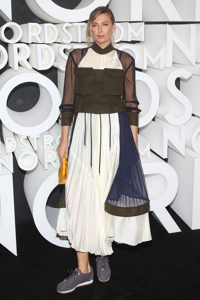 Maria Sharapova pairs a pleated Sacai Fall 2019 dress with sheer sleeves and structured cargo pockets for a modern mix of athletic edge and couture detail