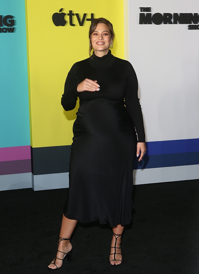 Ashley Graham makes a sleek maternity statement at The Morning Show premiere in a long-sleeve black midi dress, finishing the streamlined silhouette with delicate strappy heels that add lift without sacrificing elegance