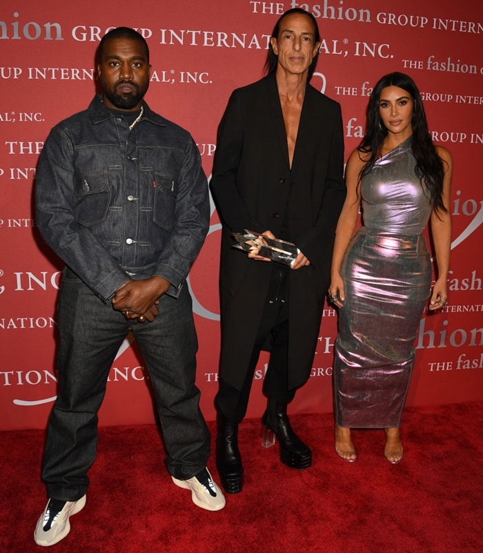 Kanye West pairs a mismatched Levi’s denim ensemble with chunky Yeezy sneakers, standing alongside Rick Owens and Kim Kardashian in her metallic Rick Owens gown and clear Manolo Blahnik sandals at the 2019 FGI Night of Stars Gala