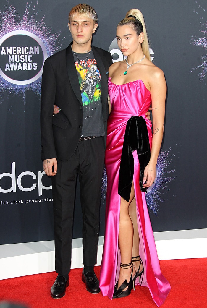 Dua Lipa coordinated her custom pink Miu Miu gown with black Attico satin pumps, while Anwar Hadid contrasted the glamour in an Iron Maiden tee layered beneath a tailored black suit