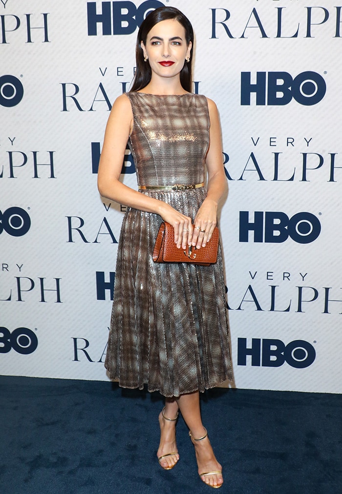 Camilla Belle pairs her Ralph Lauren sequin-embellished plaid dress with delicate gold ankle-strap sandals, adding a subtle metallic lift that complements the dress’s shimmering texture and vintage-inspired silhouette