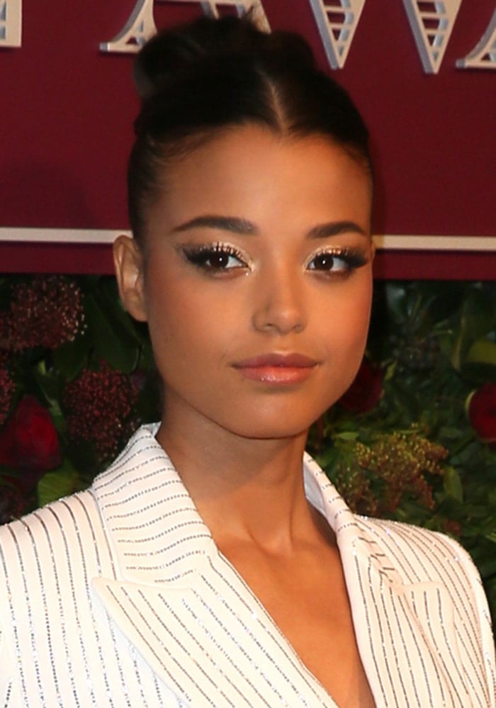 Ella Balinska shows off a chic center-parted bun and edgy winged smoky eyes, adding glam to her tailored look